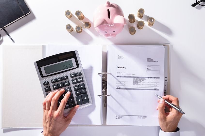 Elevated View Of Businessman Calculating Invoice With Piggybank And Coins On Desk